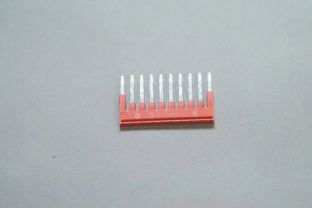 Rohelement mit 10 Kontaktstiften auf rotem Träger, geeignet für elektrische Verbindungen, hergestellt von Brötje.