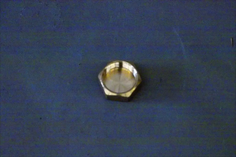 Brötje-Kappe aus Metall mit sechseckiger Form und glatter Innenseite, auf einer grauen Unterlage platziert.