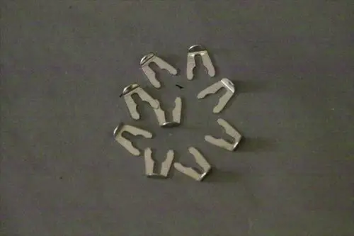 Metallene Arretierclips in Form von U-Objekten, angeordnet in einem kreisförmigen Muster auf dunklem Hintergrund, geeignet für Rohrverbindungen, Marke Brötje.