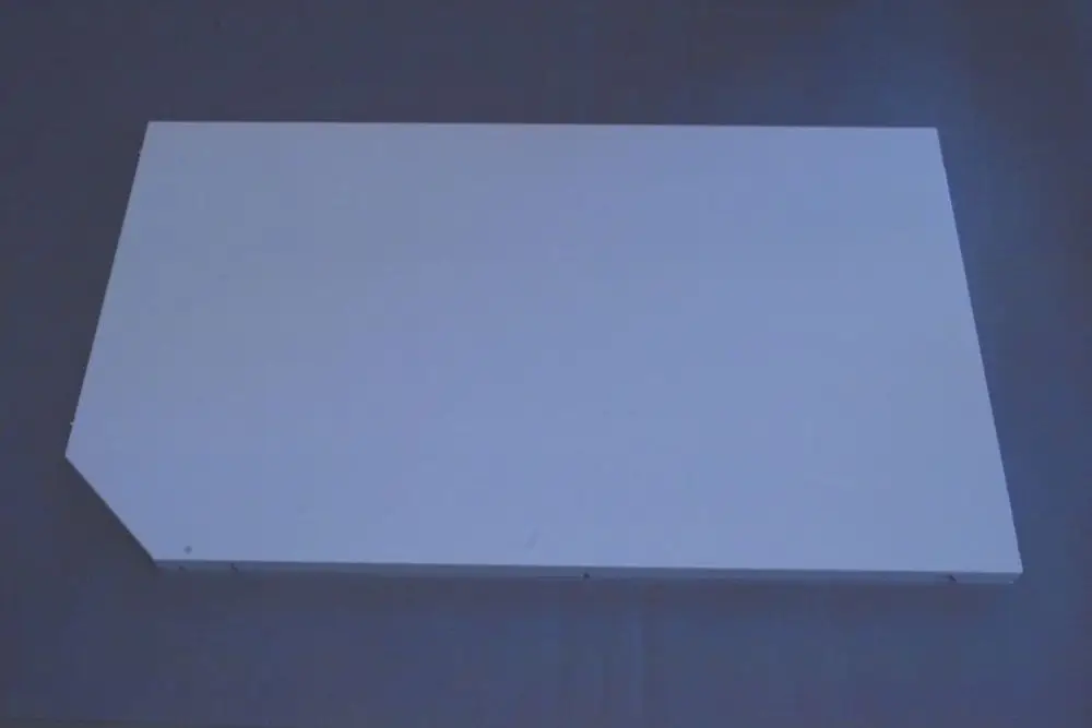 Rechteckige, weiße Verkleidung mit einer schrägen Kante, geeignet für die Montage an einem Brötje-Gerät. Sichtbare Schraubenlöcher an einer der Längsseiten.