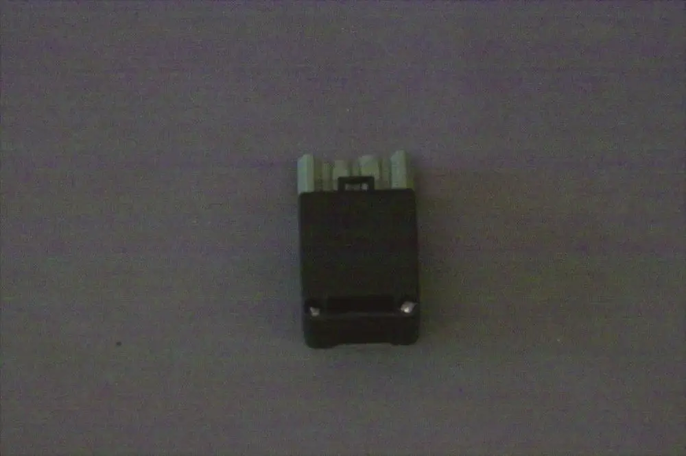 Brötje Steckdose, schwarz mit mehreren Anschlüssen. Sichtbar sind vier Metallkontakte, die auf einen Einsatz von elektrischen Leitungen hinweisen.