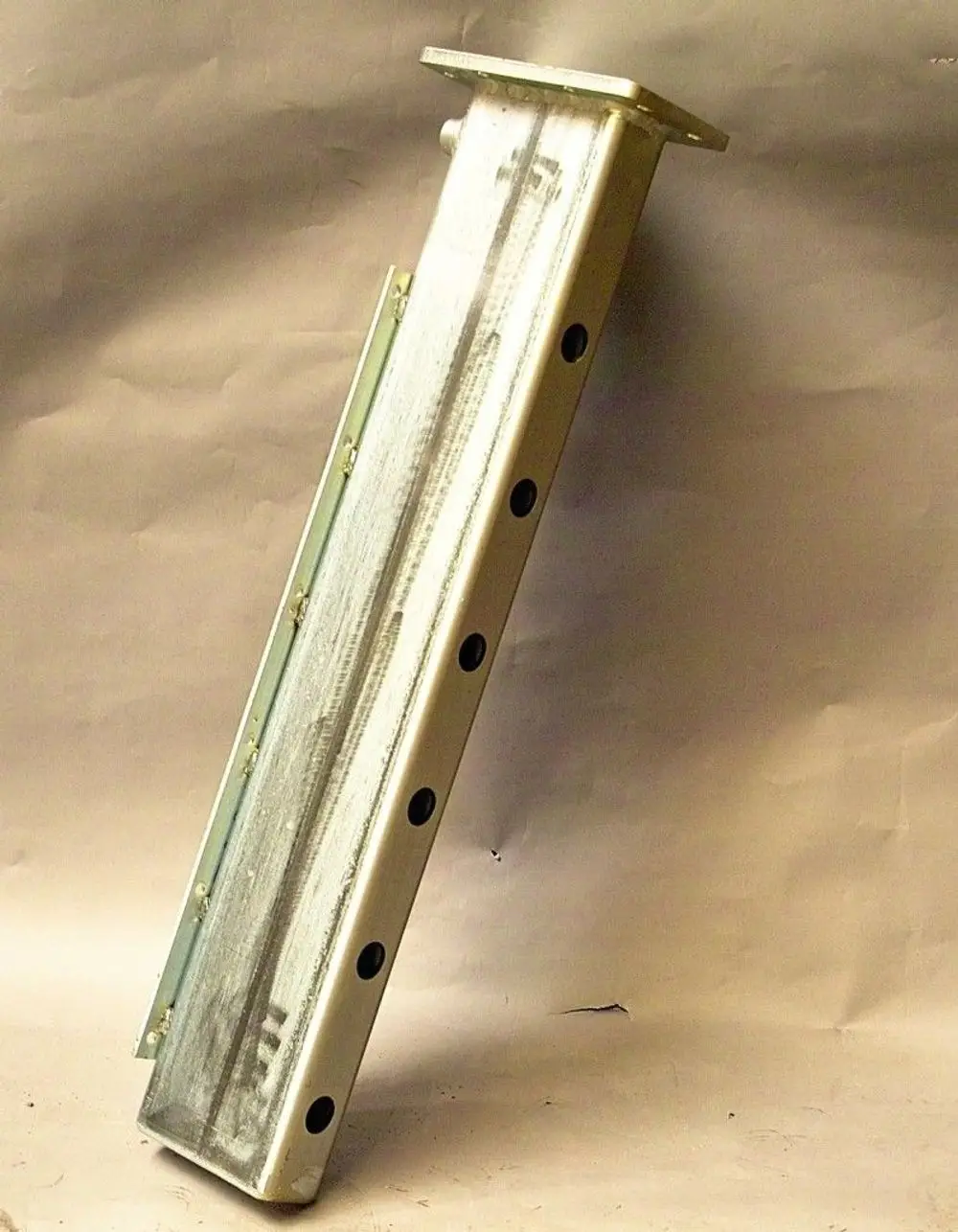 Brötje-Rücklaufverteiler in vertikaler Position, aus Metall, mit mehreren Bohrlöchern für Befestigung, zeigt einfache, funktionale Bauweise.