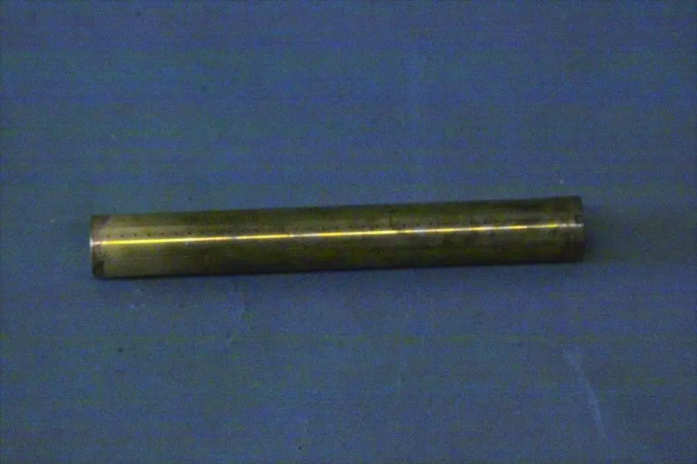 Metallrohr in goldener Farbe, auf einer blauen Fläche liegend. Einfache, zylindrische Form, ohne erkennbare Beschriftung. Möglicherweise Teil eines Brötje-Verteilers.
