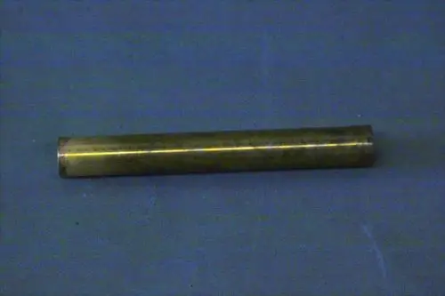 Metallrohr in goldener Farbe, auf einer blauen Fläche liegend. Einfache, zylindrische Form, ohne erkennbare Beschriftung. Möglicherweise Teil eines Brötje-Verteilers.