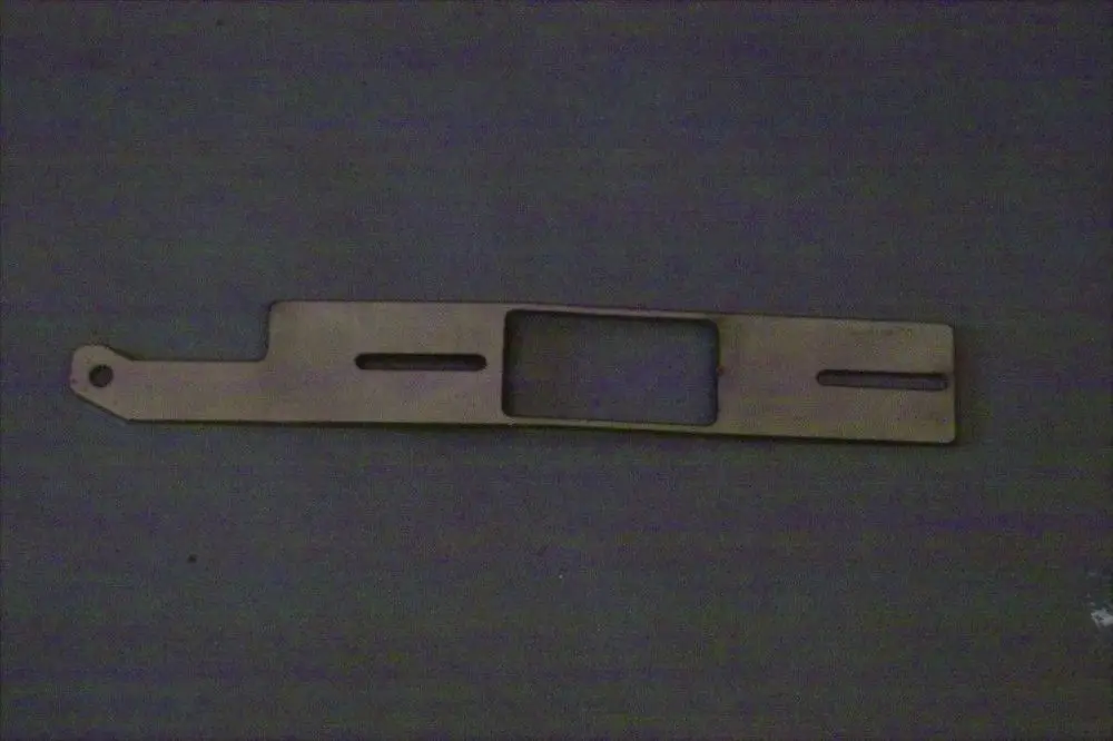 Luftschieber von Brötje, längliche Metallplatte mit Ausschnitten und einer Öse, liegt auf einer dunklen Oberfläche.