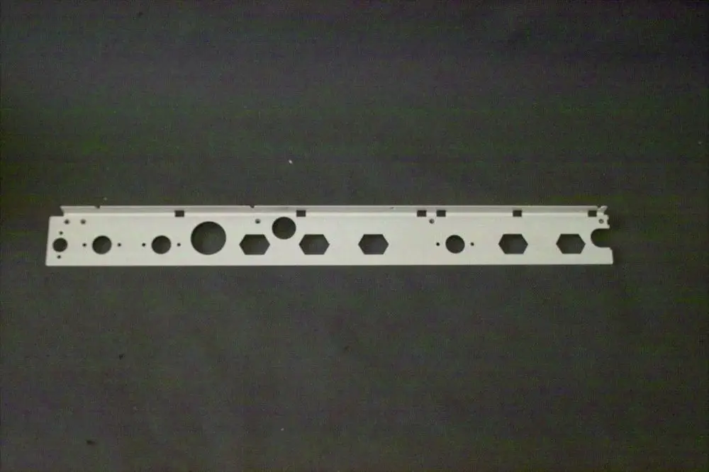 Weißes Fixierblech mit verschiedenen Ausschnitten in kreis- und sechseckiger Form, geeignet für Brötje Produkte. Schlichte, lange Bauform auf dunklem Hintergrund.