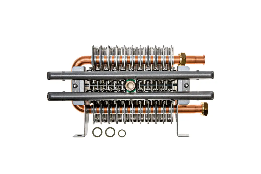 Brötje Heizkörper mit Kupferrohren und Aluminiumrippen, montiert auf einer Halterung, mit mehreren O-Ringen im Vordergrund.