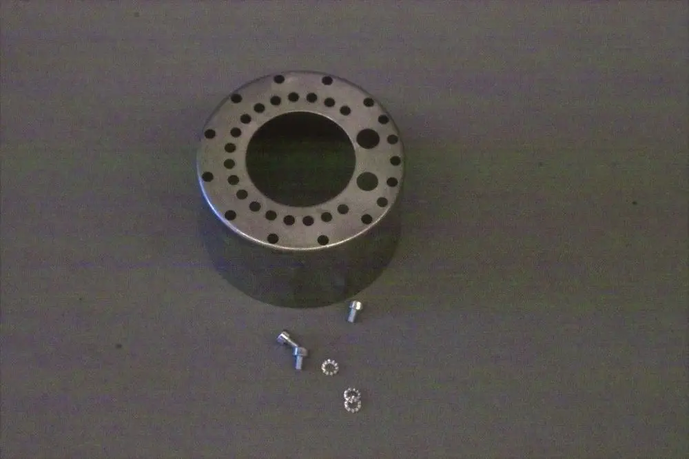 Metallene Stauscheibe mit kreisförmigem Loch in der Mitte und mehreren kleinen Bohrungen im Randbereich, begleitet von zwei Schrauben und einem Unterlegring, geeignet für Brötje-Produkte.