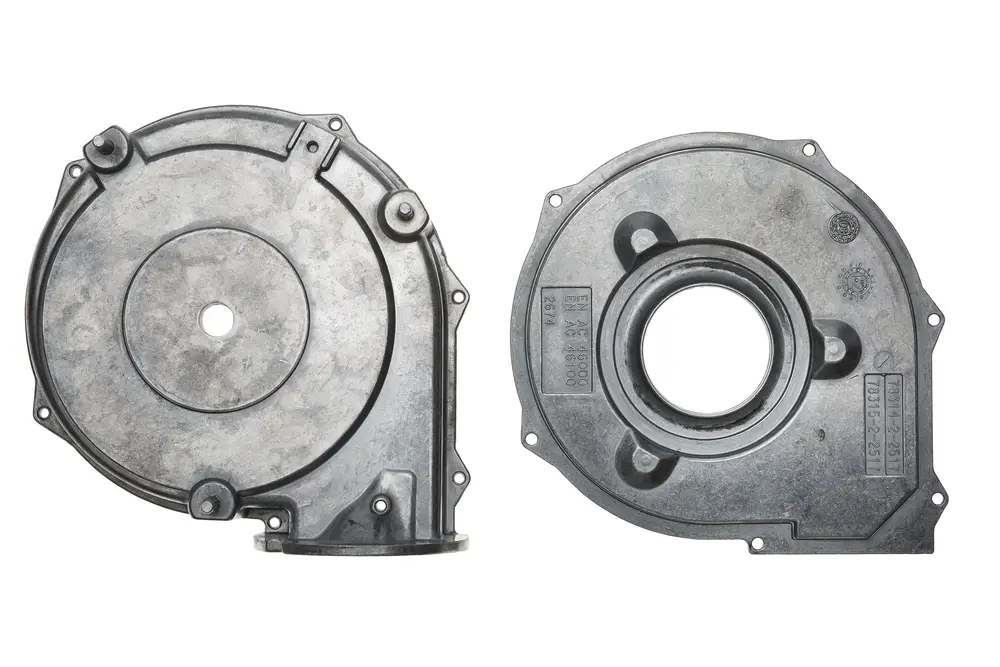 Brötje Gebläsedeckel in metallischer Ausführung, mit mehreren Befestigungslöchern und einer zentralen Öffnung, gezeigt aus zwei Perspektiven.