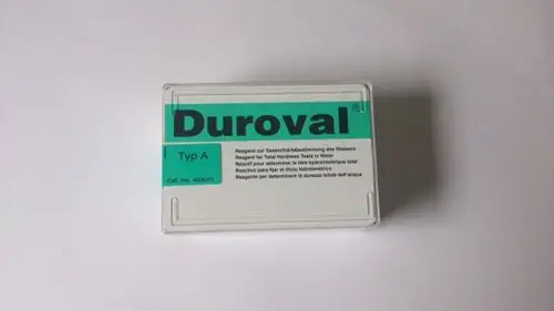 Testkit von Brötje zur Bestimmung der Gesamtwasserhärte. Verpackt in einem klaren Behälter mit grünem Aufkleber und mehrsprachigen Anweisungen für die Anwendung.