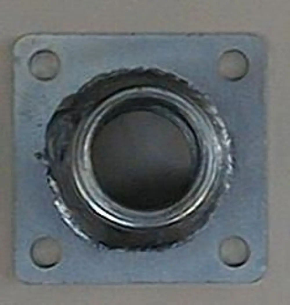 Metallischer Düsenhalter mit quadratischer Grundplatte und zentralem Gewinde, geeignet für Brötje Heizsysteme. Vier Montagelöcher für Befestigung sichtbar.
