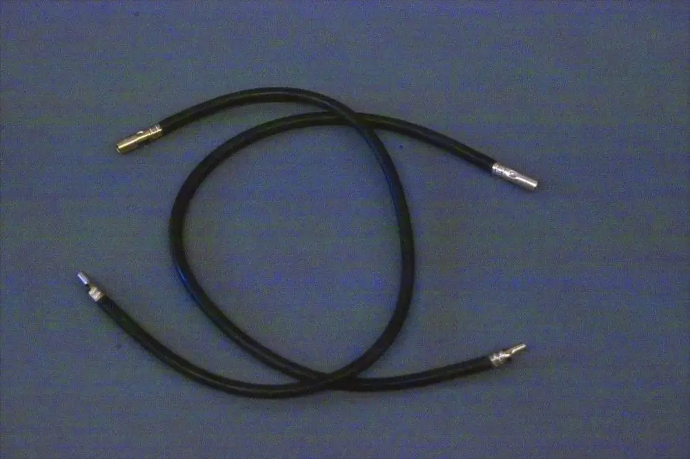 Schwarze Kabel mit Metallanschlüssen, die typisch für Zündleitungen sind, möglicherweise von der Marke Brötje. Sie liegen übereinander auf einer grauen Unterlage.