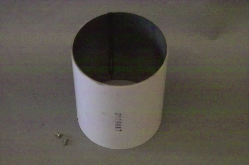 Produkt von Brötje, zylindrisches Flammrohr in neutraler Farbe, mit zwei kleinen Schrauben daneben, auf einer hellen Oberfläche platziert.