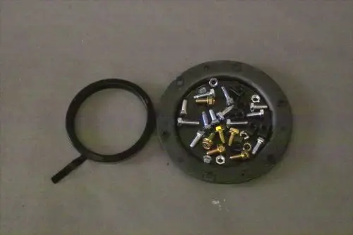 Brötje Reinigungsdeckel mit verschiedenen Schrauben und Bolzen in der Mitte, umgeben von einem runden, schwarzen Rahmen.