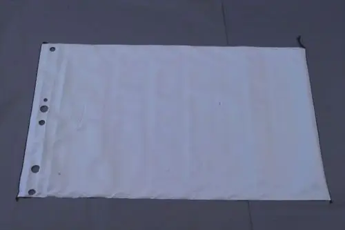 Weißes, rechteckiges Material mit Ösen an einer langen Seite, vermutlich zur Abdeckung oder Verkleidung, auf grauem Untergrund. Brötje ist als mögliche Marke erkennbar.