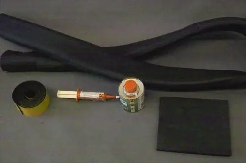 Brötje Reparatur-Set mit zwei schwarzen Schläuchen, Gummi-Rolle, Kleber, Dose sowie einem Quadrat aus schwarzem Material für Reparaturarbeiten.