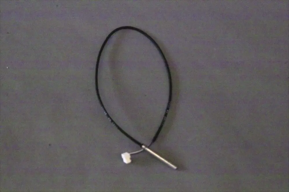 Schwarzes Kabel mit einem weißen Anschluss und einem metallischen Stift. Er scheint zu einem Brötje Speicherfühler zu gehören.
