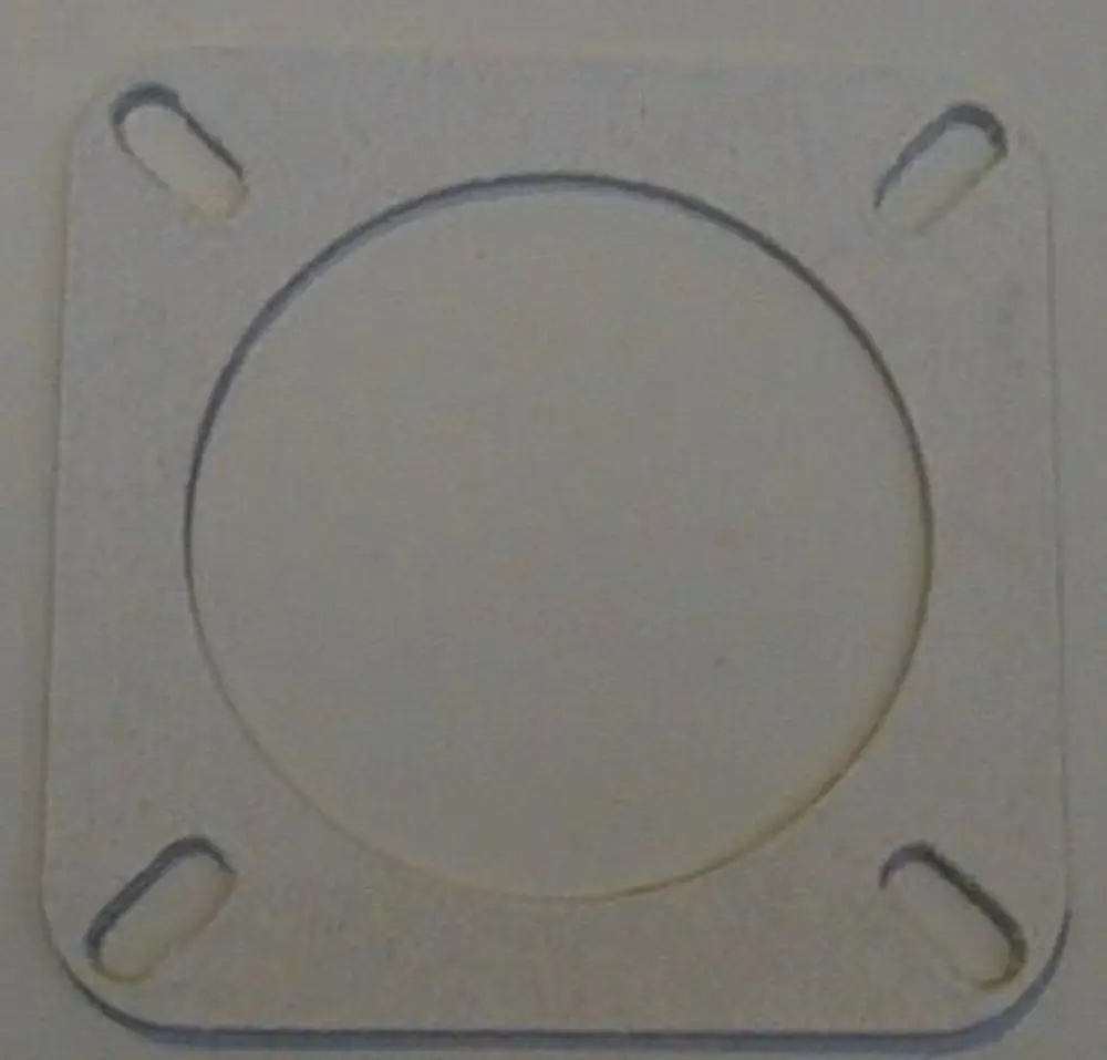 Brötje Kesselflanschdichtung aus flachem Material mit einem zentralen Loch und vier seitlichen Aussparungen zur Befestigung.