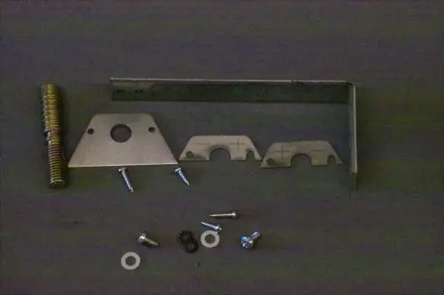 Verschiedene Metall- und Schraubenteile, einschließlich Halterungen und Unterlegscheiben, auf einem dunklen Untergrund, möglicherweise für ein Brötje Produkt.