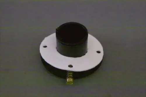 Brötje-Produkt mit runder Basis und schwarzem, hohem Zylinder. Vier Löcher in der weißen Unterlage zur Befestigung. Eine Schraube ist in die Basis integriert.