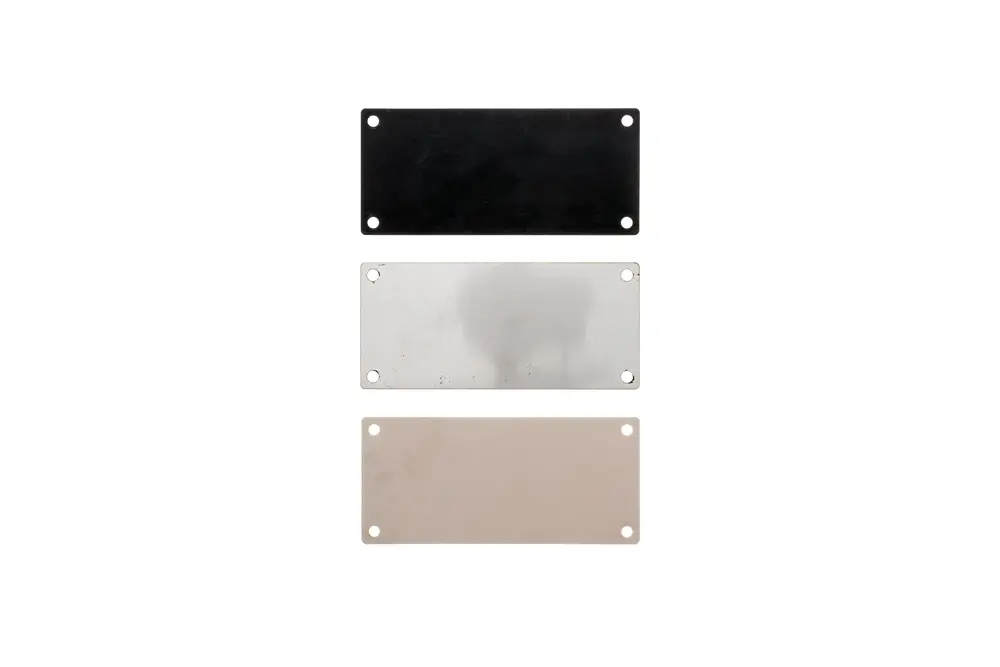 Drei rechteckige Deckel in Schwarz, Silber und Beige mit je zwei Löchern zur Montage, möglicherweise für Brötje Heizsysteme oder Installationen.