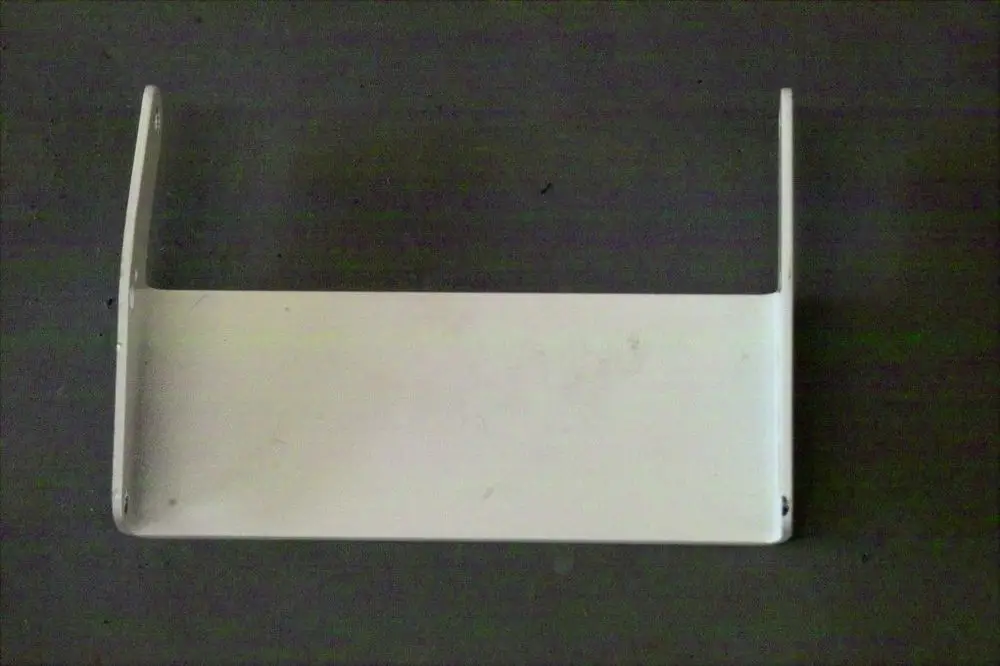 Weißes, flaches Metallteil mit zwei seitlichen Haltebügeln, möglicherweise ein Scharnierblech für eine Brötje-Heizungsanlage.