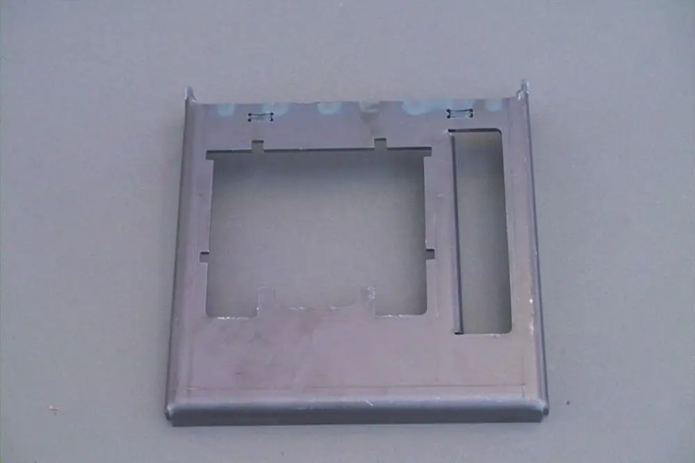 Graue metallene Platte mit Ausschnitten, vermutlich für eine Brennerplatte. Sie ist ohne weitere Beschriftungen oder Details, die auf das Produkt von Brötje hinweisen.
