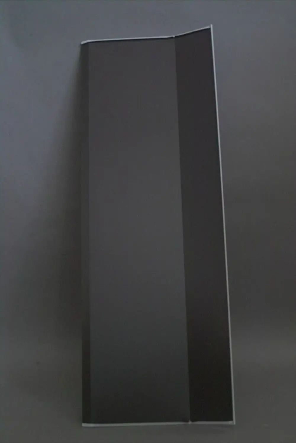 Schwarzes, flaches Blech im Hochformat mit einer leicht gebogenen Kante, das als Teil eines Brötje-Dachsystems verwendet wird.