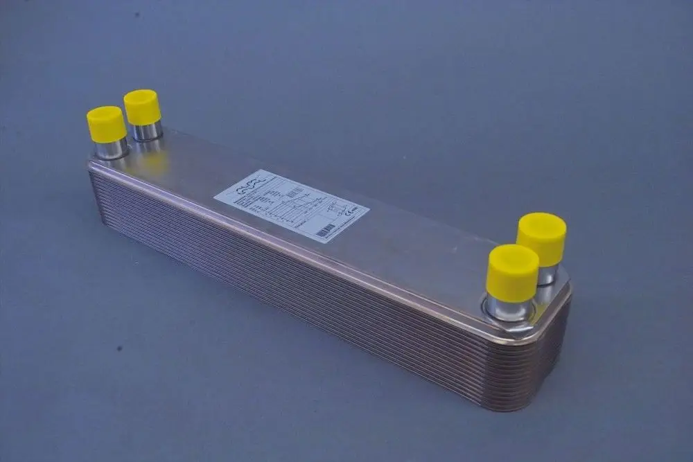 Wärmetauscher aus Metall mit vier gelben Schutzkappen an Anschlüssen, gekennzeichnet mit technischen Informationen. Produkt stammt von der Marke Brötje.