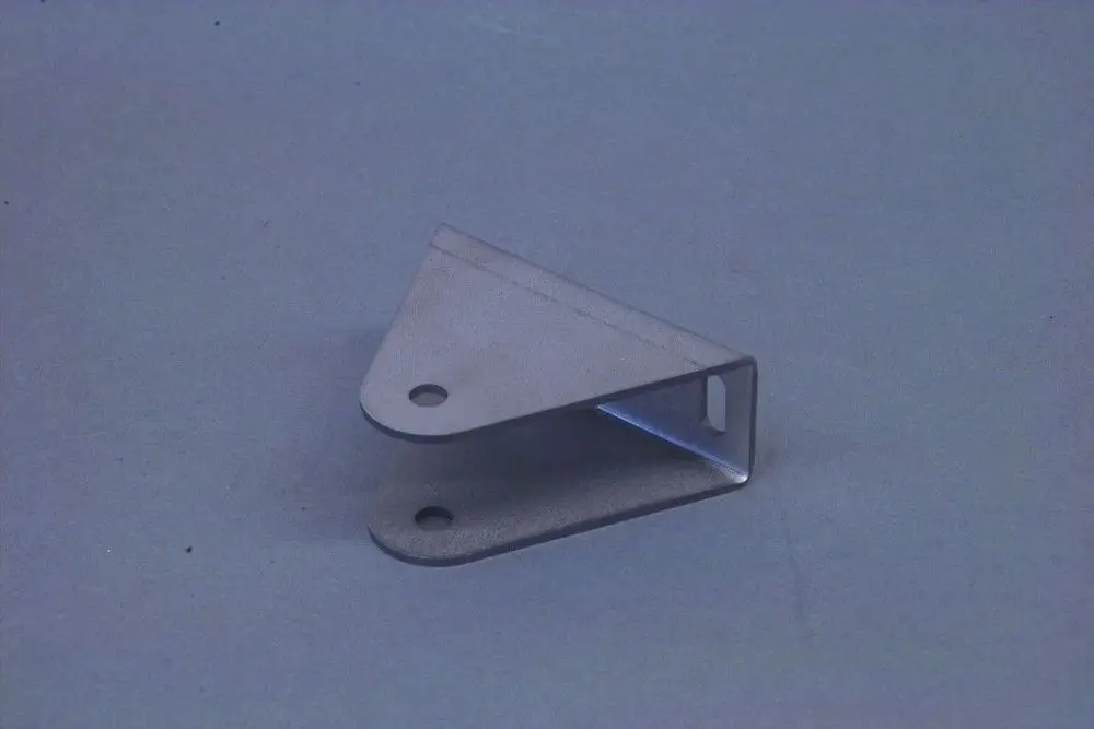 Brötje Aufstellfuß aus Metall, L-förmige Halterung mit zwei Löchern zur Befestigung, auf grauem Hintergrund.