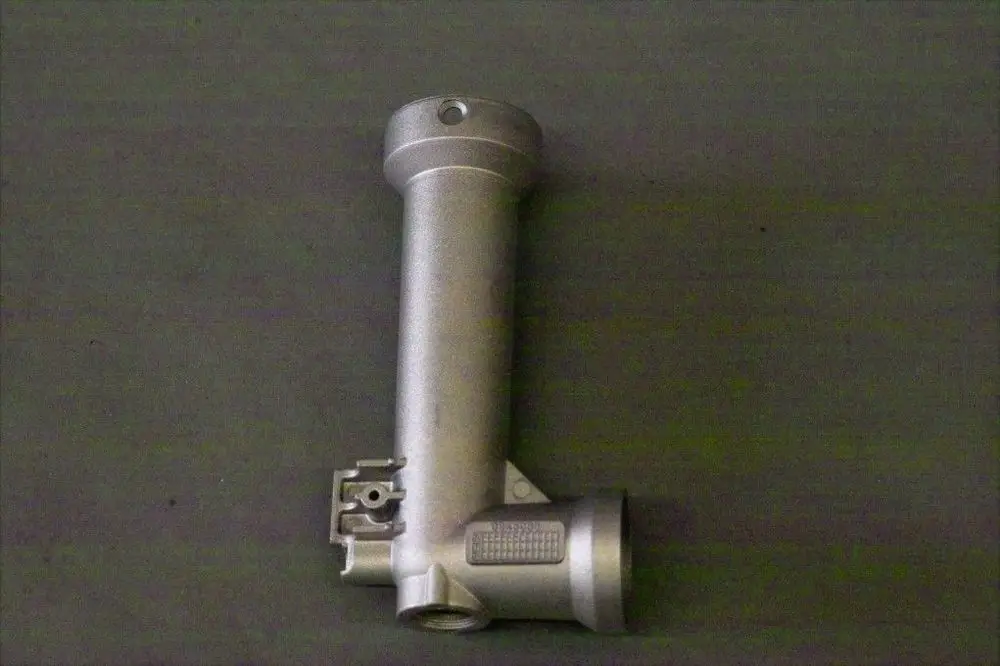 Brötje Produkt, metallisches Bauteil mit einem Rohr und einer seitlichen Anschlussmöglichkeit, auf grauem Hintergrund.