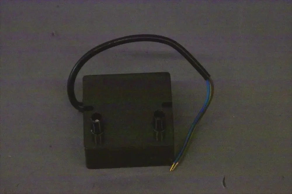 Brötje Zündtrafo mit zwei Anschlüssen und einem Kabel, auf grauem Untergrund. Das Produkt hat eine kompakte, rechteckige Form.