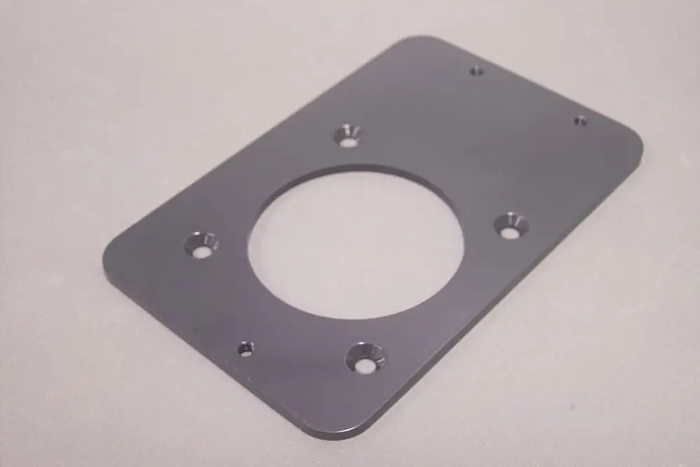 Schwarze Adapterplatte von Brötje mit kreisförmigem Ausschnitt und mehreren Befestigungslöchern. Fläche ist rechteckig und glatt.