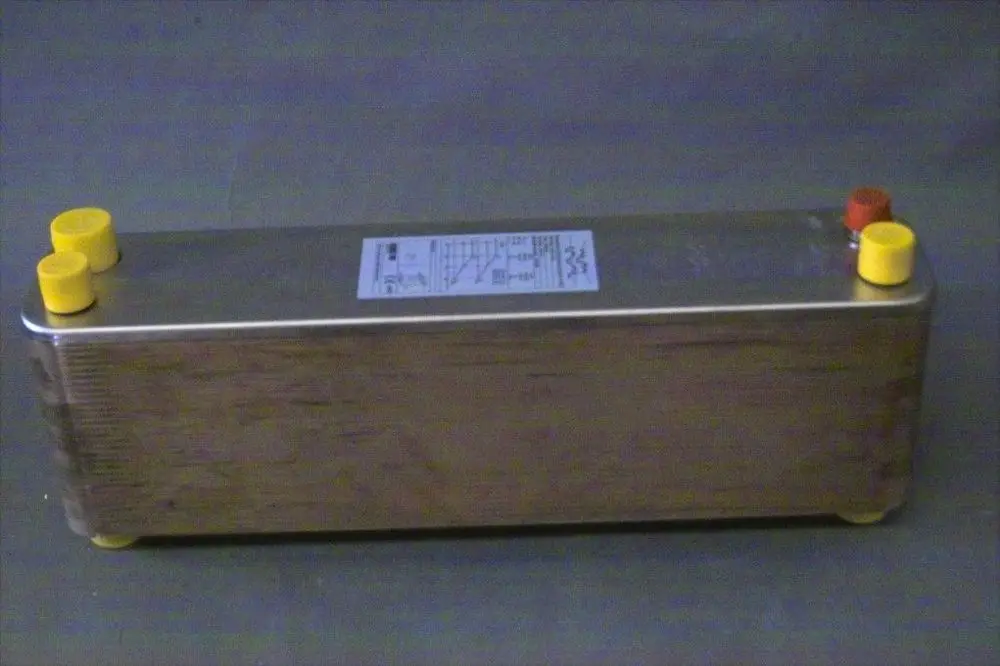 Brötje Verdampfer mit einem länglichen, metallischen Gehäuse und mehreren Anschlüssen in gelb und rot. Auf einer Seite ist ein Etikett mit technischen Informationen angebracht.