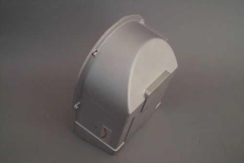 Metallische Ansaugöffnung von Brötje, auf einer neutralen grauen Fläche. Die Struktur ist kompakt mit abgerundeten Kanten und einer glatten Oberfläche.