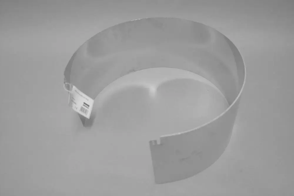 Metallisches Brennraumblech von Brötje, in gebogener Form, ohne erkennbare Maße oder spezifische Details. An einer Seite ist ein Etikett angebracht.