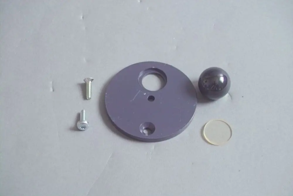 Purple Montageplatte mit Loch in der Mitte, begleitend ein grauer Glasball, zwei Schrauben und eine kleine Linse. Teile zur Installation eines Brötje Schauglases.