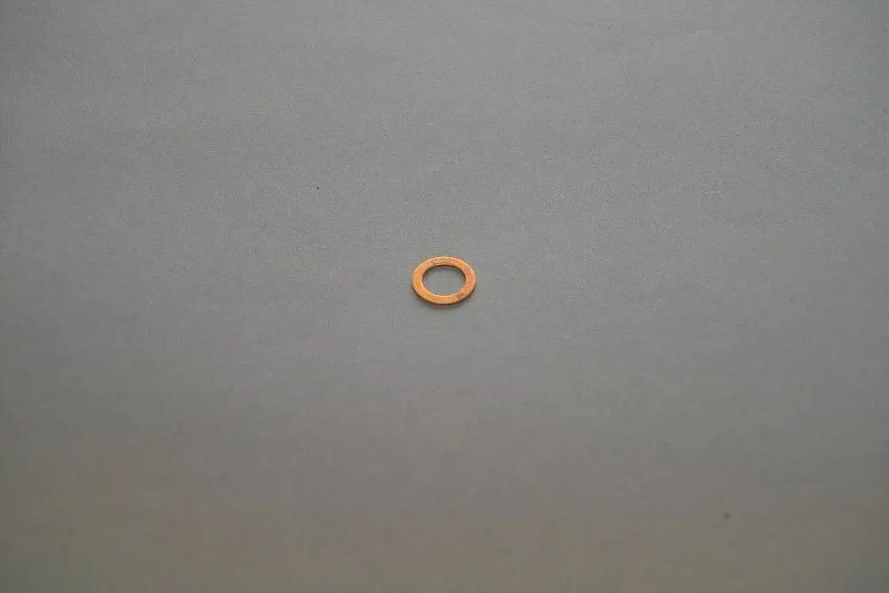 Kupferfarbene Dichtung von Brötje, in Ringform, auf grauem Untergrund. Das Bild zeigt die Dichtung ohne weitere Gegenstände oder Beschriftungen.