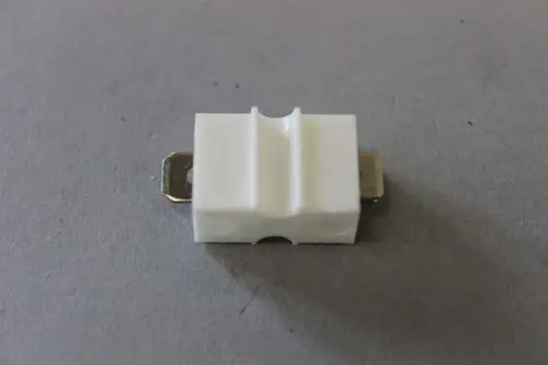 Brötje Verlängerungslasche in Weiß mit metallischen Kontaktpunkten. Das Produkt wird zur Verbindung oder Verlängerung in Heizsystemen verwendet.