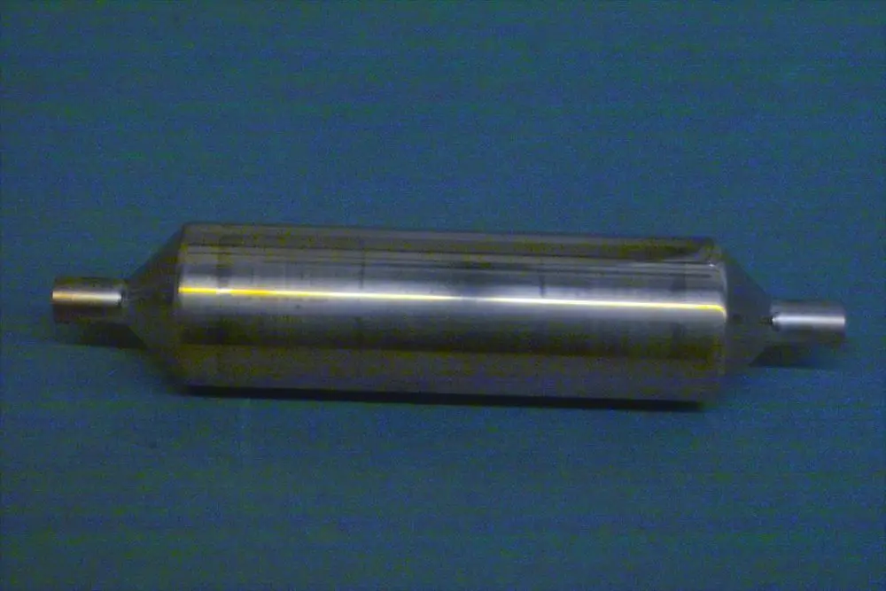 Metallischer Schalldämpfer der Marke Brötje, zylindrische Form mit zwei offenen Enden, auf blauem Untergrund abgebildet.