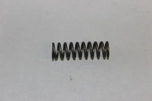 Schwarze Druckfeder, spiralförmig gewickelt, auf grauem Hintergrund. Teil einer Brötje-Anlage, möglicherweise für eine Stellschraube.
