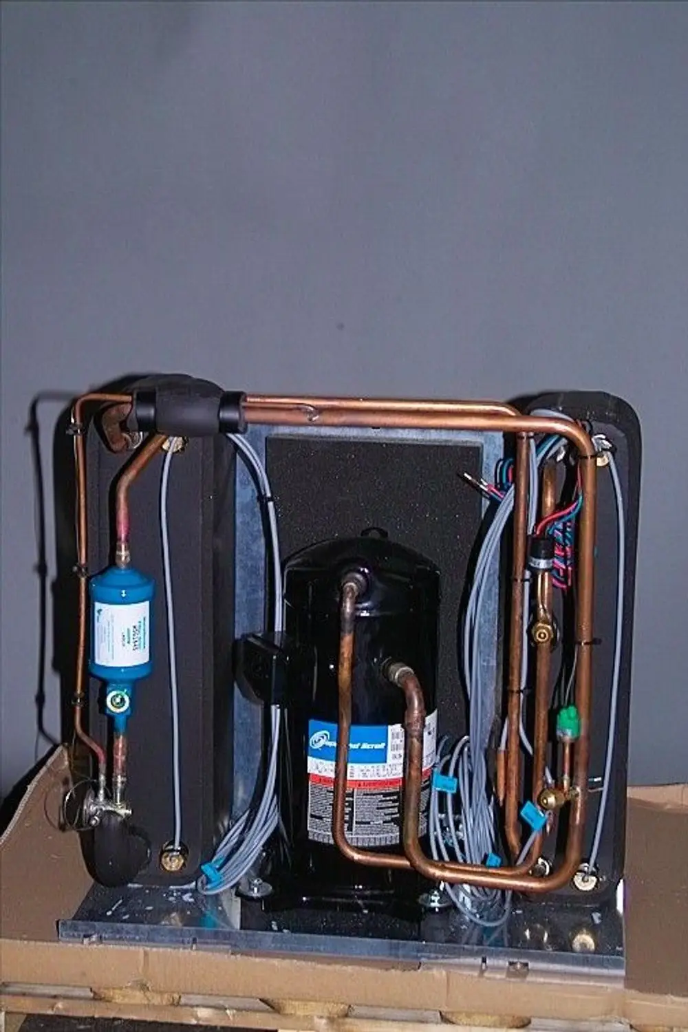 Brötje Kälteteil mit Kupferrohren und Verdichter, sichtbar auf einer Fläche mit Isolierung, einige elektrische Leitungen sind ebenfalls sichtbar.