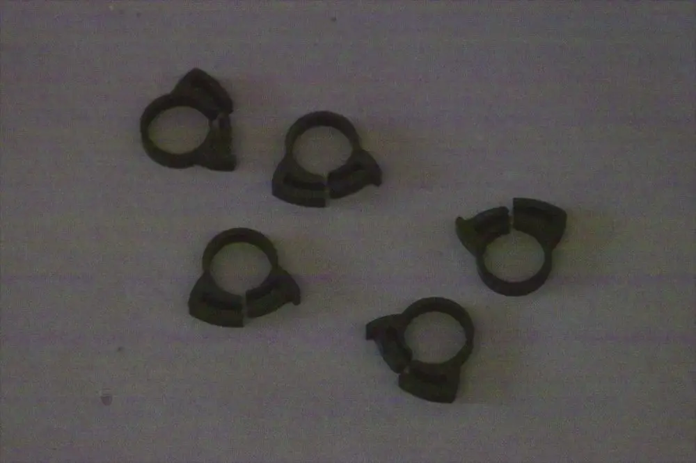 Fünf schwarze Schlauchklemmen von Brötje auf einer hellen Oberfläche. Die Klemmen haben eine charakteristische Form mit einer Öffnung zur Befestigung von Schläuchen.