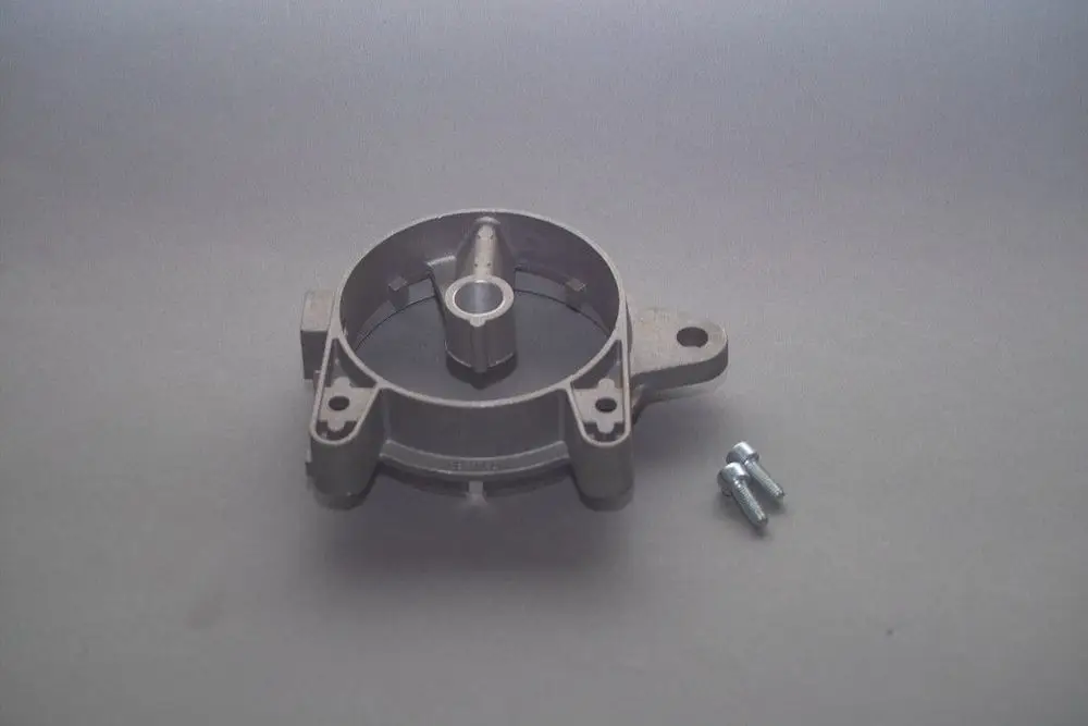 Brennerflansch von Brötje in grauer Metalloptik mit einem zentralen Anschluss und zwei Befestigungslöchern, daneben zwei Metall-Schrauben.