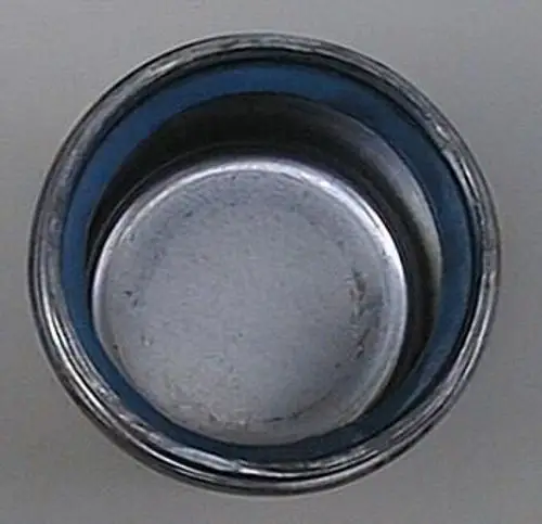 Runder Metalldeckel mit einem inneren blauen Rand, geeignet für den Einsatz bei Brötje-Produkten. Sichtbare Abnutzungserscheinungen im Inneren der Abdeckung.