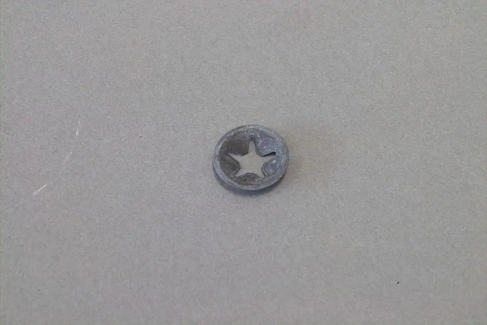Kleiner, runder Metallring mit sternförmiger Aussparung, möglicherweise ein Klemmring von Brötje für die Befestigung von Metallstiften.