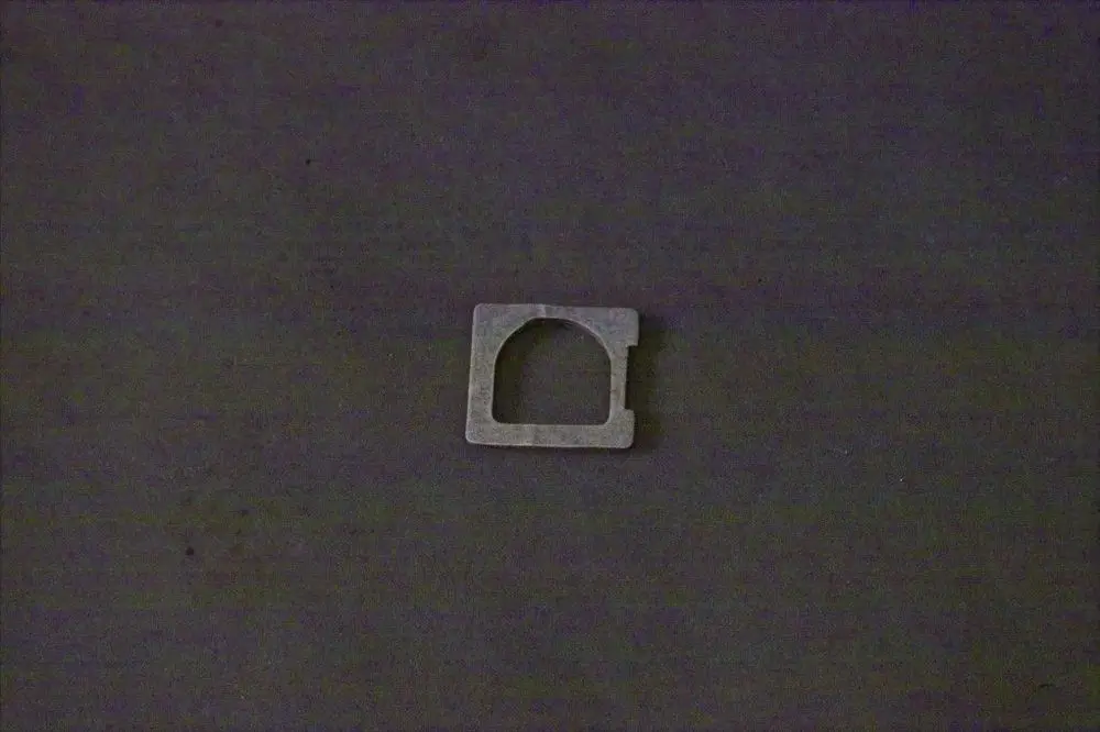 Metallene Dichtung mit quadratischer Form und einem Ausschnitt, geeignet für Anwendungen von Brötje. Auf grauem Untergrund.