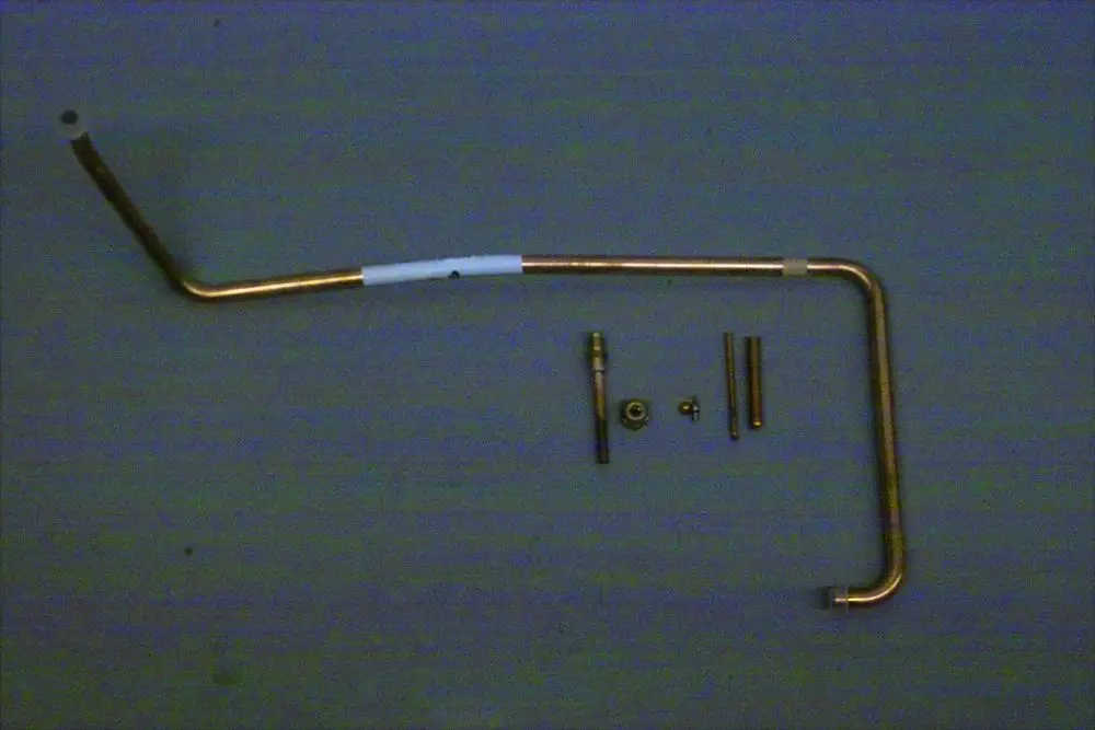 Brötje Flüssigkeitsleitung aus Kupfer in L-Form, zusammen mit verschiedenen Metallteilen, die zur Befestigung oder Verbindung dienen.
