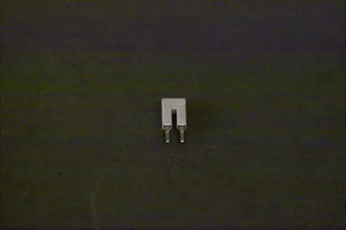 Brötje Verbindungselement in Form einer kleinen Brücke mit zwei Stiften, auf schwarzem Untergrund dargestellt.