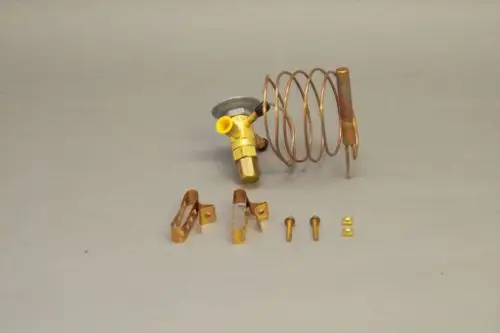 Brötje Expansionsventil mit einer Metallspirale, einem kupferfarbenen Anschluss und verschiedenen Halterungen sowie Schrauben auf neutralem Hintergrund.